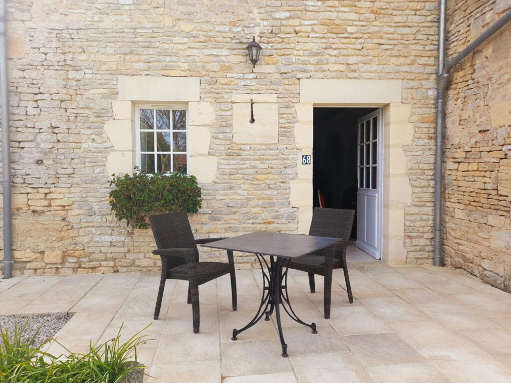Stone Terrace con tavolo e sedie, davanti a un muro di pietra del Mathan Manor, che offre un&#39;atmosfera tranquilla.