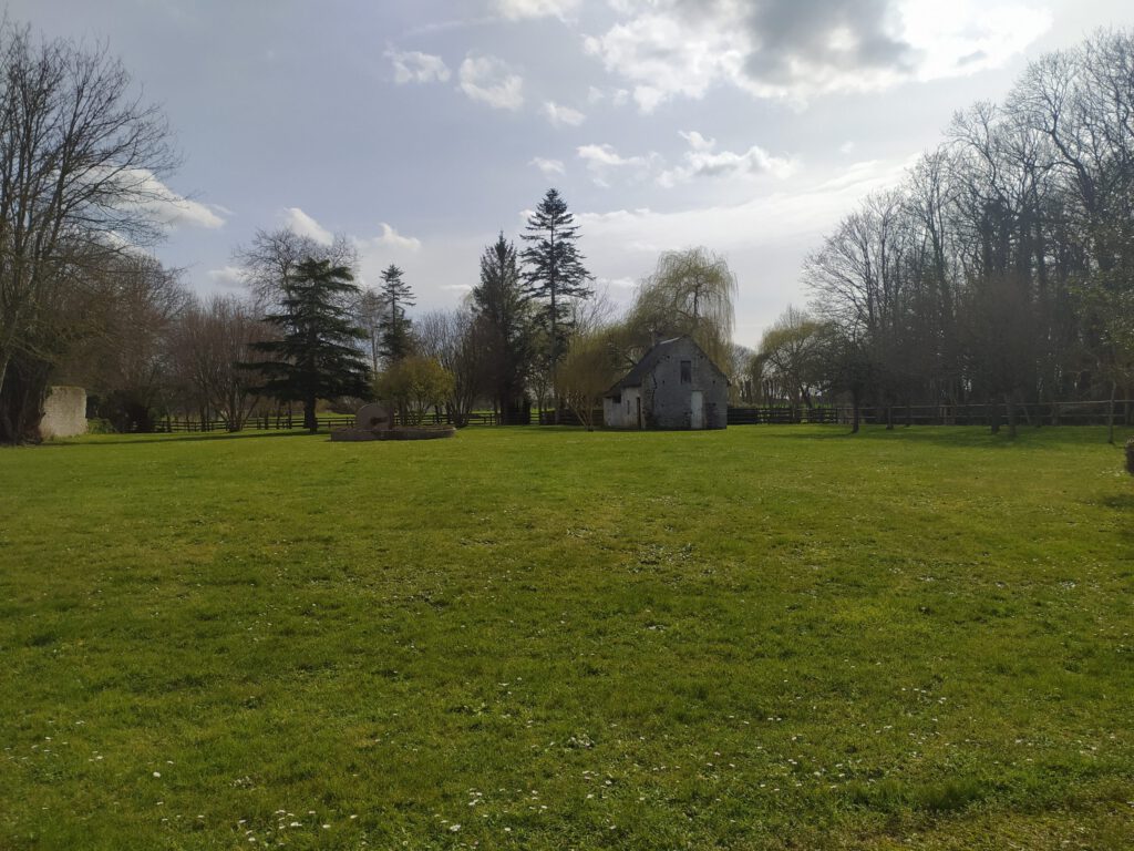 Vasto parco verde che circonda il maniero di Mathan, con una vecchia panetteria in pietra e alberi maestosi.