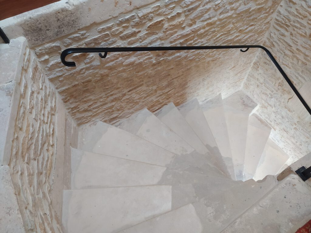 Scade in pietra che conduce a uno spazio comodo nel Mathan Manor, circondato da pareti di pietra naturale.