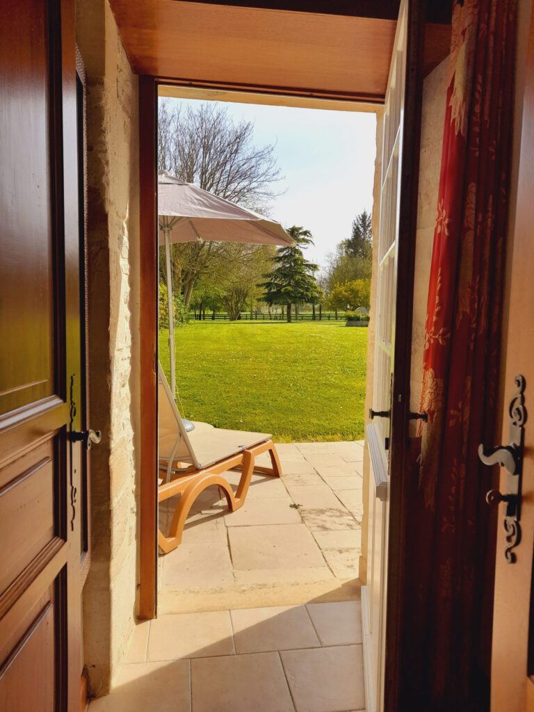 Vista di una stanza più alta del Mathan Manor, che si apriva su un giardino verde con una sken -secone e un parasole.