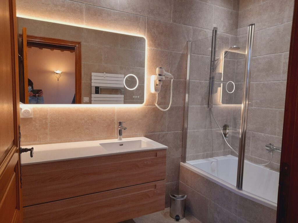Bagno moderno con lavello elegante, specchio luminoso e doccia in vetro, in un ambiente raffinato e caldo.