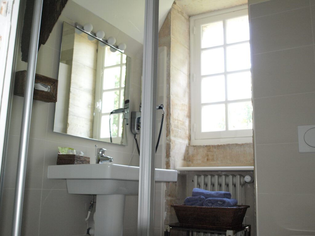 Bagno moderno Mathan Manor, con specchio, lavandino e finestra che lascia entrare la luce naturale.