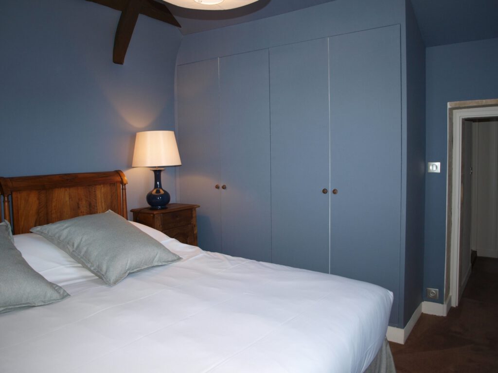 Elegante sala padronale Mathan, con letto comodo, lampade dolci e arredamento raffinato in toni di blu.