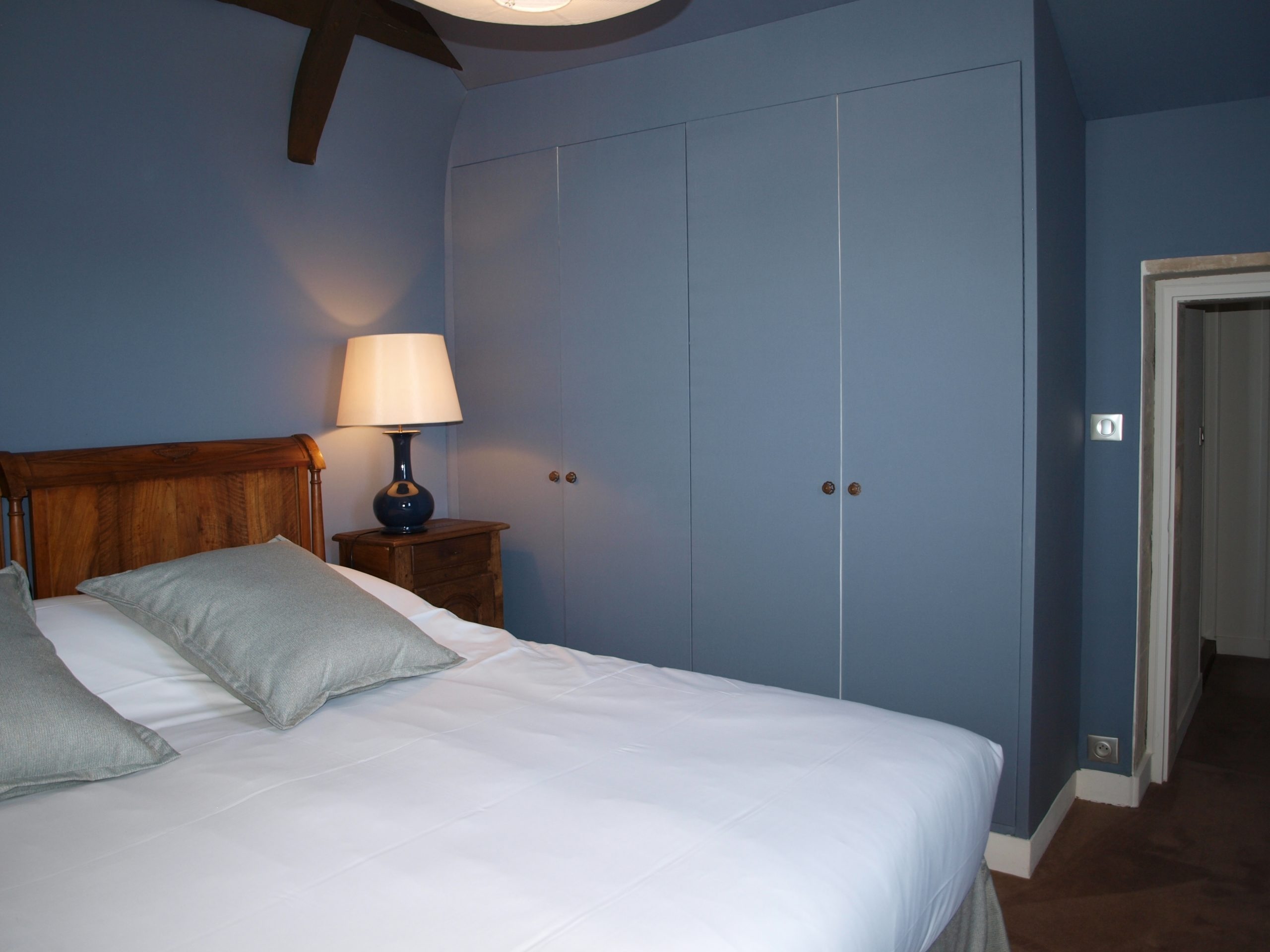 Elegante sala padronale Mathan, con letto comodo, lampade dolci e arredamento raffinato in toni di blu.