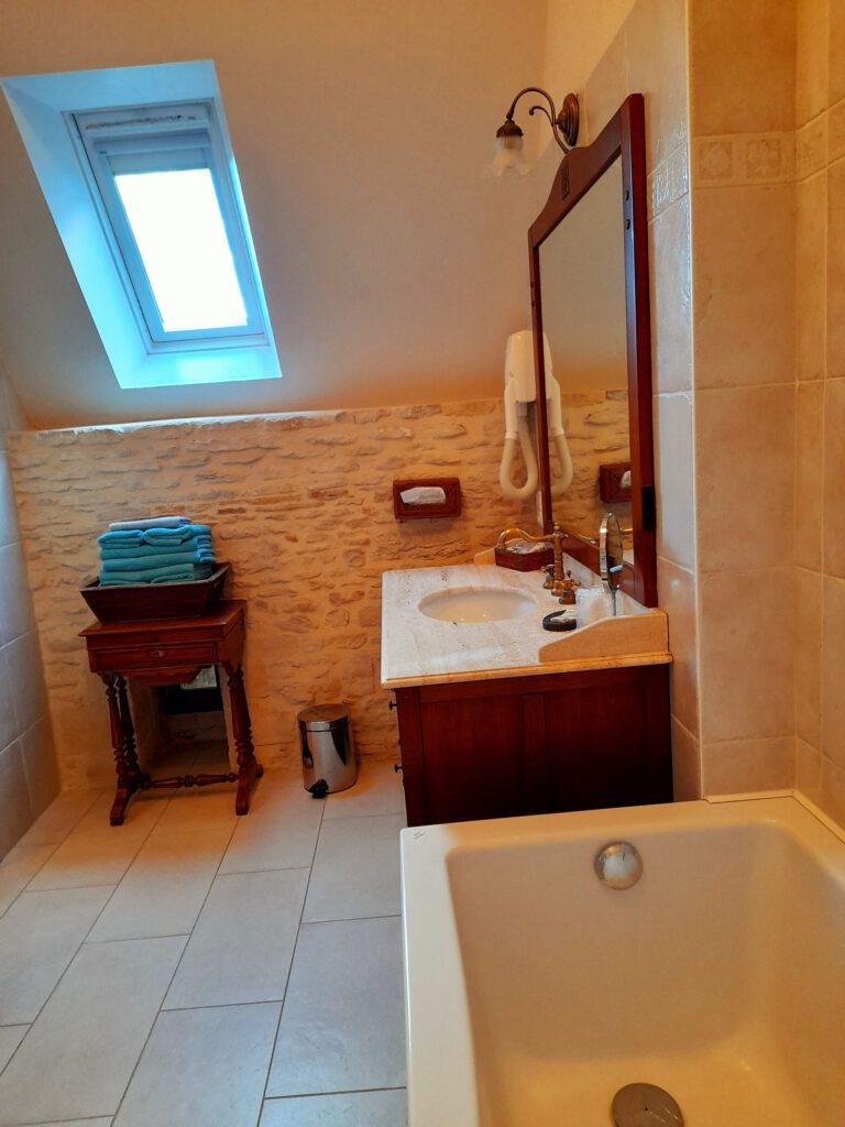 Baño brillante con bañera, fregadero, espejo y decoración de piedra. Amble atmósfera y equipo moderno.