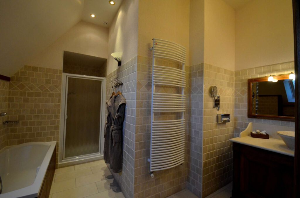 Baño elegante con bañera, ducha y almacenamiento de piedra, en un entorno moderno y cálido.