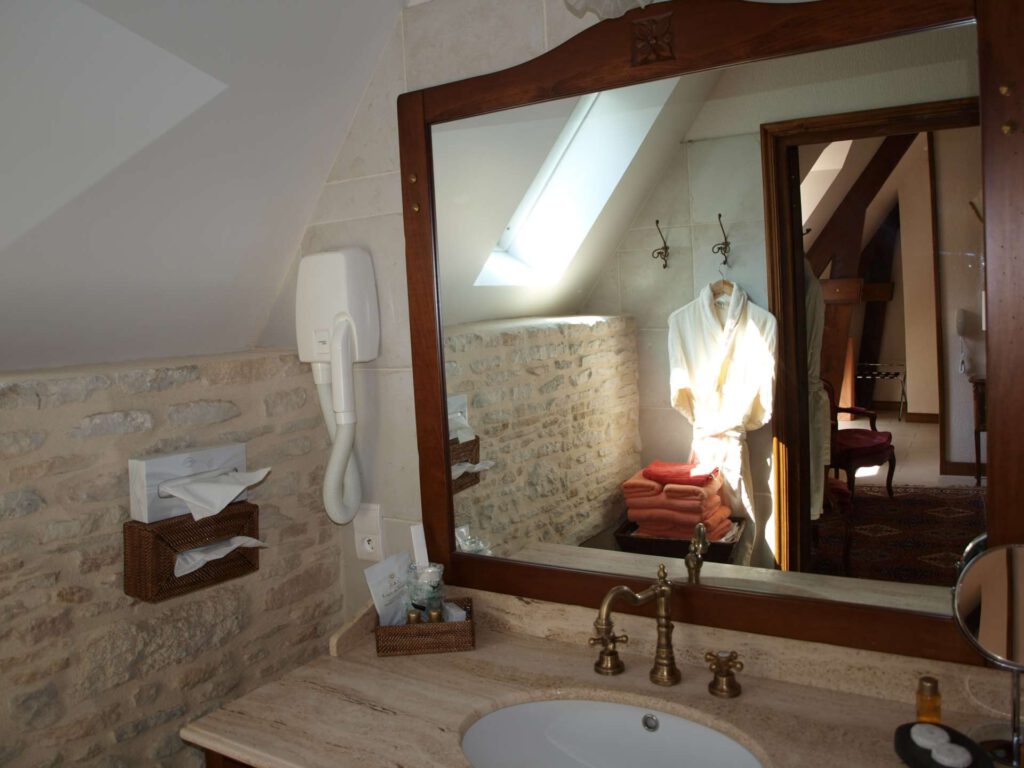 Baño elegante con fregadero de mármol, espejo y toallas cuidadosamente dispuestas. Ambiente cálido y relajado.