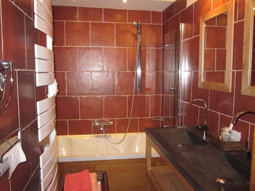 Baño con diseño moderno con barro rojo, baño y ducha, iluminación tibia.