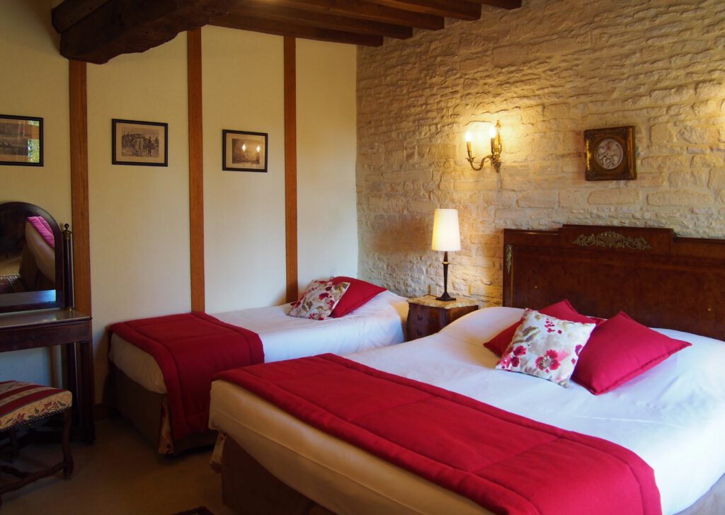 Habitación acogedora en el Mathan Manor, con camas gemelas, decoración elegante e iluminación cálida.