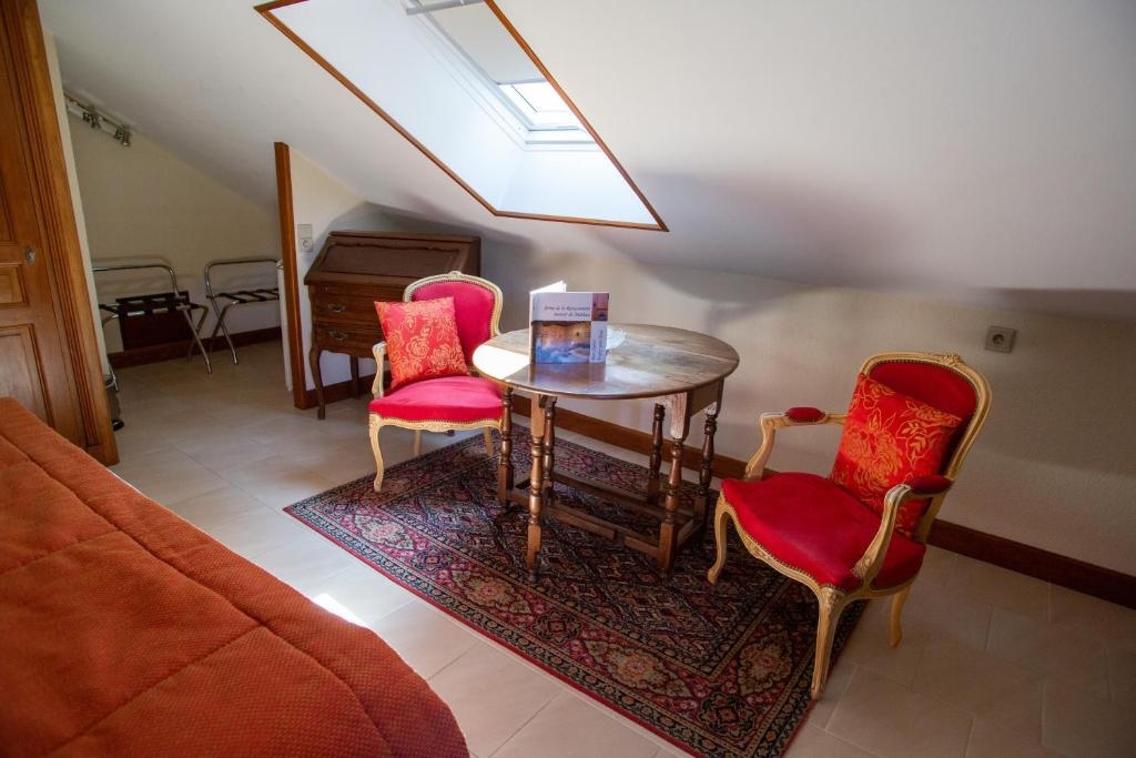 Interior de un dormitorio con Mathan Manor, con sillones rojos, una mesa y una alfombra. Atmósfera acogedora y elegante.